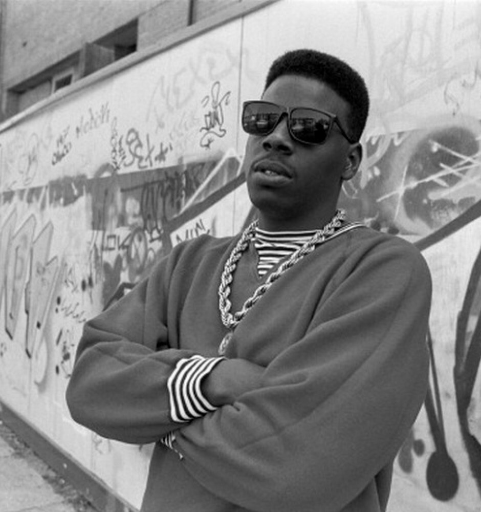 American rapper Schoolly D (Jesse Weaver) poses in front of a graffiti tagged wall on Harrow Road, London, UK, 1986. (Photo by David Corio/Redferns)